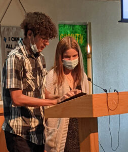 A man and a woman standing in front of a laptop