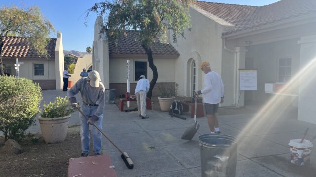 A group of people standing around a fire hydrant in front of a building