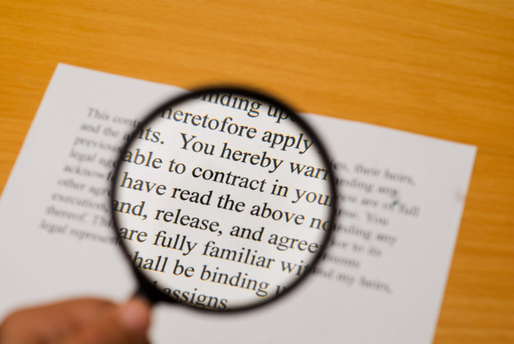Magnifying glass on a contract with selective focus on the word "contract".