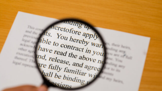 Magnifying glass on a contract with selective focus on the word "contract".