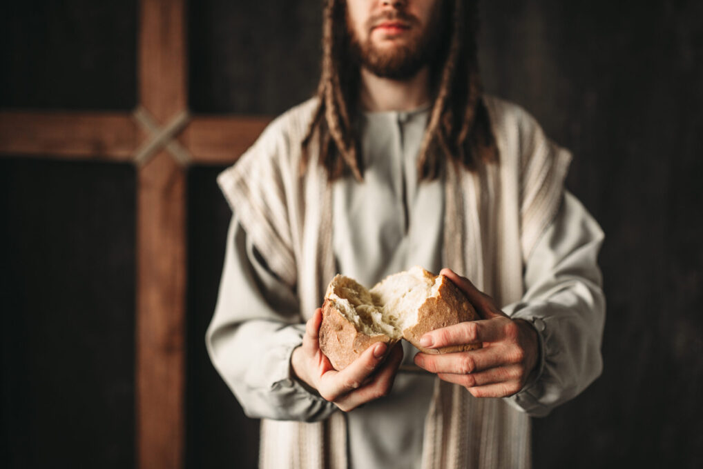 Jesus Christ gives bread to the faithful, sacred food, crucifixion cross on background.