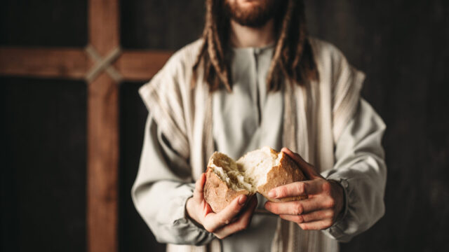 Jesus Christ gives bread to the faithful, sacred food, crucifixion cross on background.