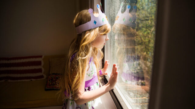 Side view of girl looking away while standing by window at home