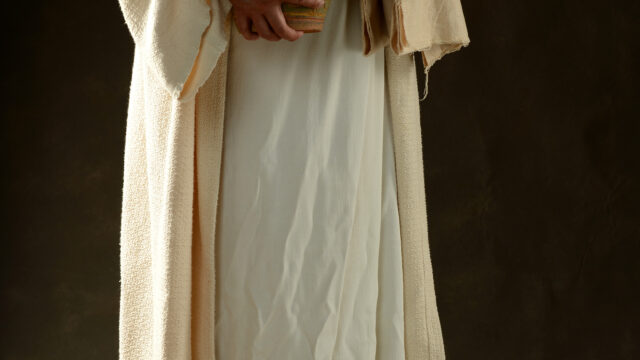 Jesus holding a jar of water standing up with a dark background