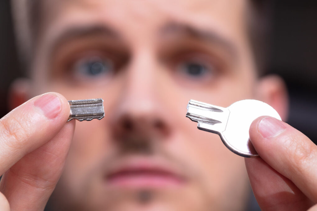 Portrait Of Shocked Man 's Hand Holding Silver Broken Key