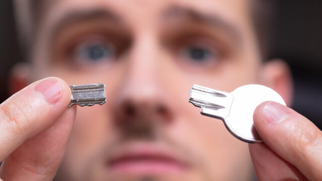 Portrait Of Shocked Man 's Hand Holding Silver Broken Key