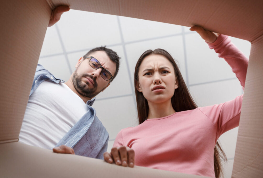 Frustrated man and woman unpacking cardboard box and looking inside. The package, delivery, surprise, gift
