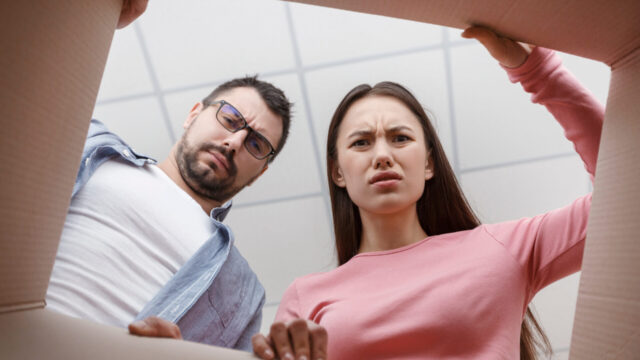 Frustrated man and woman unpacking cardboard box and looking inside. The package, delivery, surprise, gift