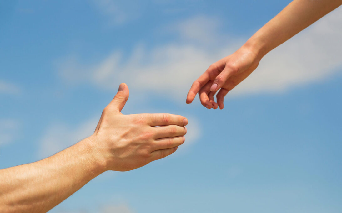 Giving a helping hand. Hands of man and woman on blue sky background. Lending a helping hand. Solidarity, compassion, and charity, rescue. Hands of man and woman reaching to each other, support.