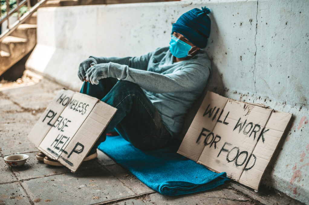 The beggars sat beside the street with a homeless message. Please help and work with food.
