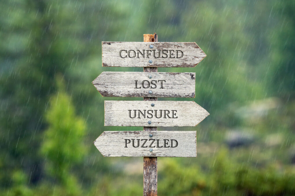 confused lost unsure puzzled text on wooden signpost outdoors in the rain.