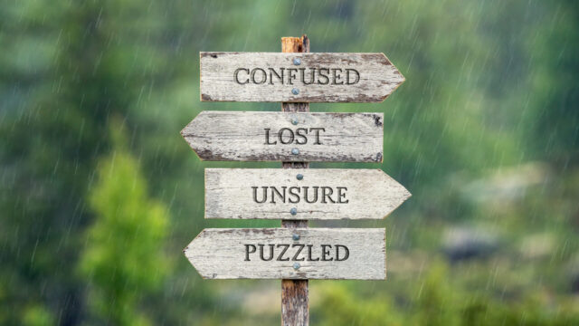 confused lost unsure puzzled text on wooden signpost outdoors in the rain.