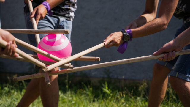 Teambuilding game for group of people for getting team spirit and increase friendship for colleagues. Team game with ball and sticks.
