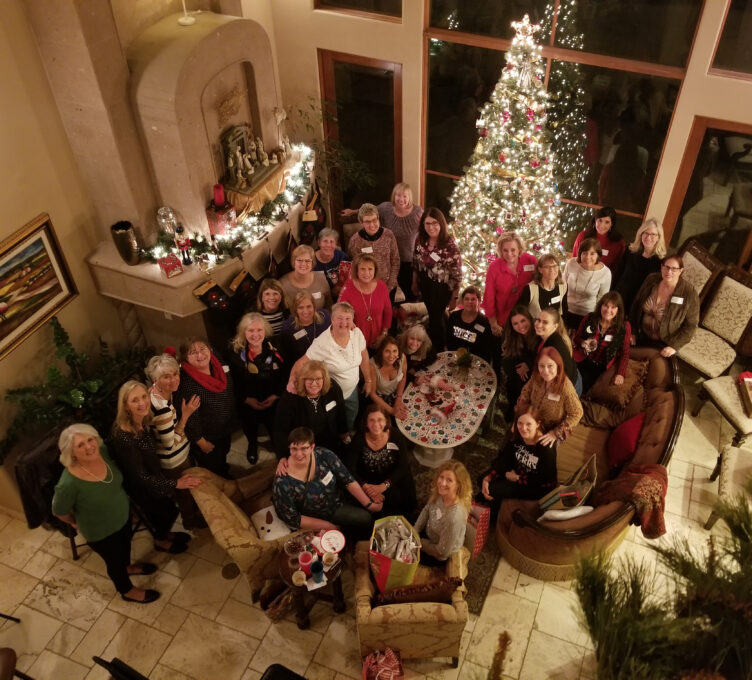 A group of people standing next to a christmas tree