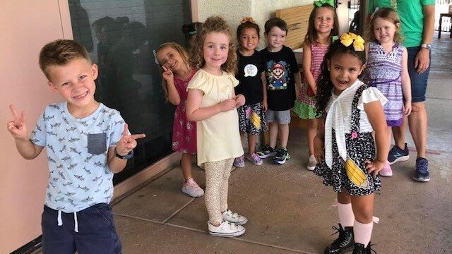 A small child is holding a bunch of little kids posing for a picture