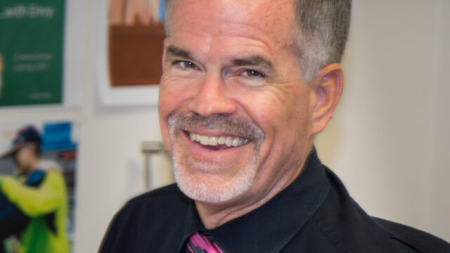 A man wearing a suit and tie smiling at the camera