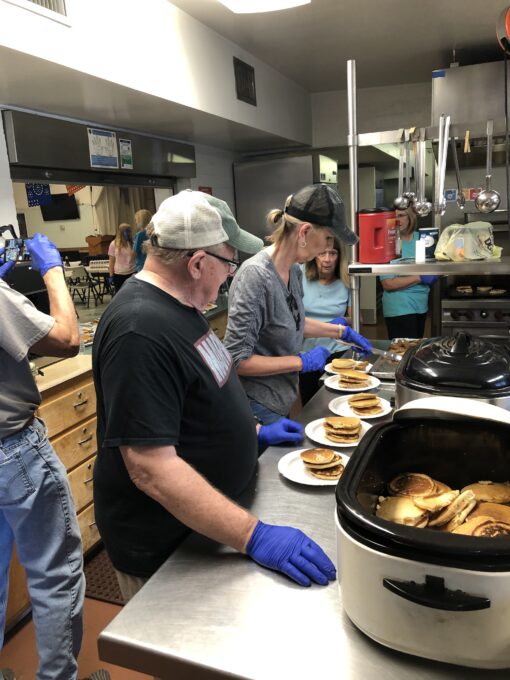 A group of people standing in a kitchen preparing food