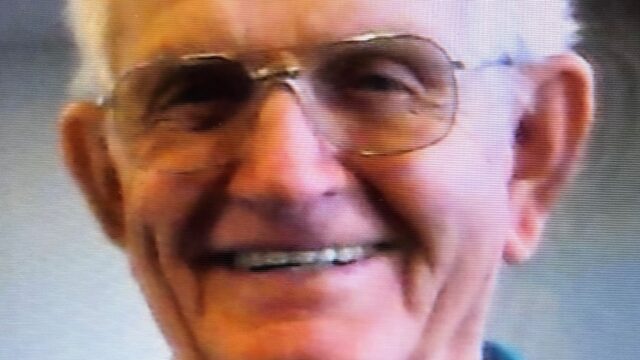 A close up of a man wearing glasses and smiling at the camera