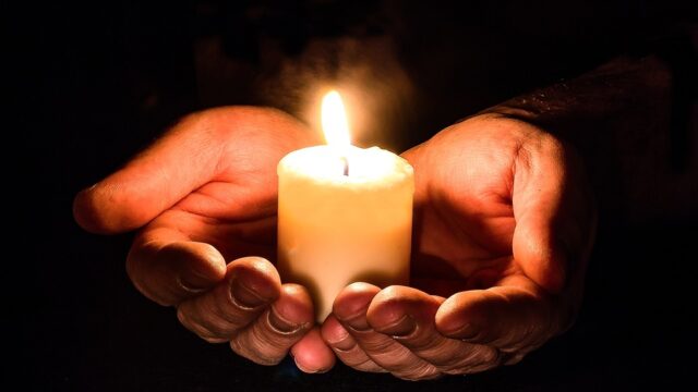 A hand holding a lit candle